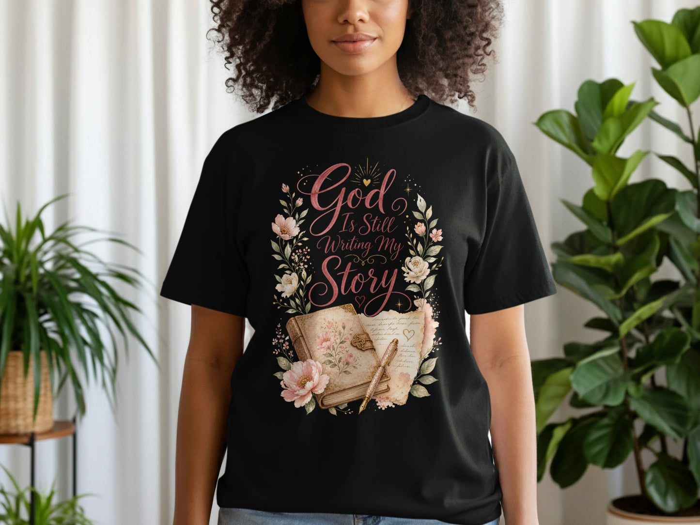 Black t-shirt with "God Is Still Writing My Story" text and floral design.