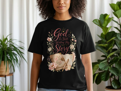 Black t-shirt with "God Is Still Writing My Story" text and floral design.