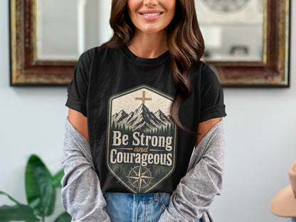Black cotton t-shirt with mountains, compass, cross, and "Be Strong and Courageous" text.