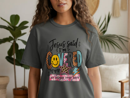 Dark grey t-shirt featuring "Jesus said I'm COVERED no stress over here" graphic.