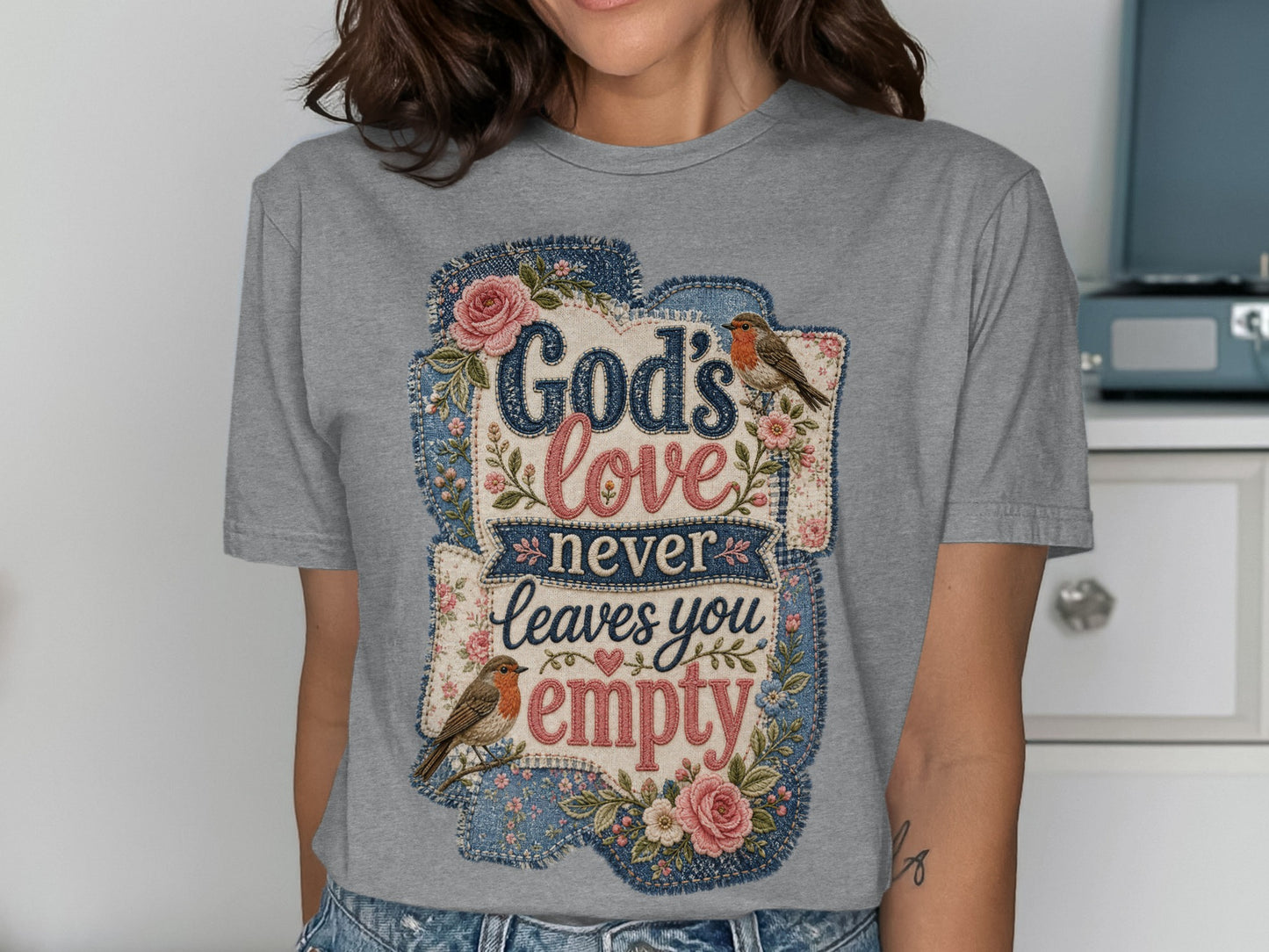 Grey t-shirt with "God's love never leaves you empty" text, flowers, and birds.