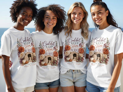 Women wearing white t-shirts with "Couldn't Keep Him Buried" and empty tomb design.