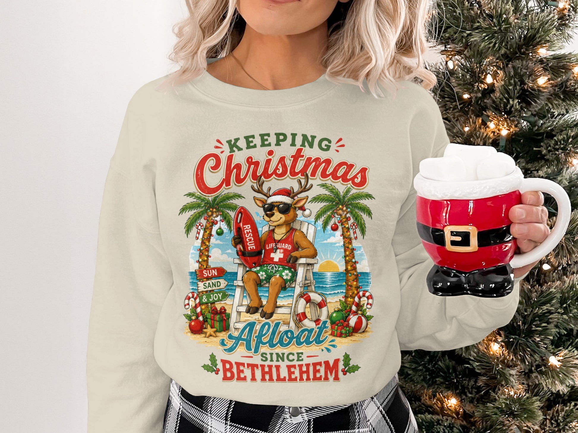 Cream sweatshirt with a holiday graphic of a reindeer lifeguard at a beach.