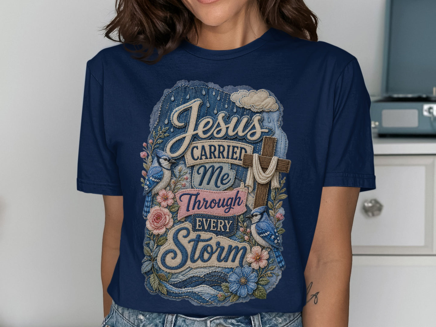 Navy t-shirt with "Jesus Carried Me Through Every Storm" text and bluebirds.