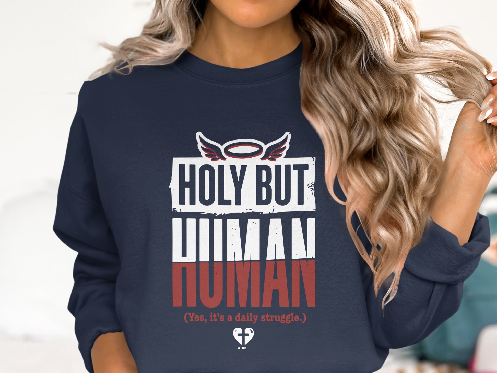 Navy sweatshirt with text "Holy but Human" and a small heart logo.