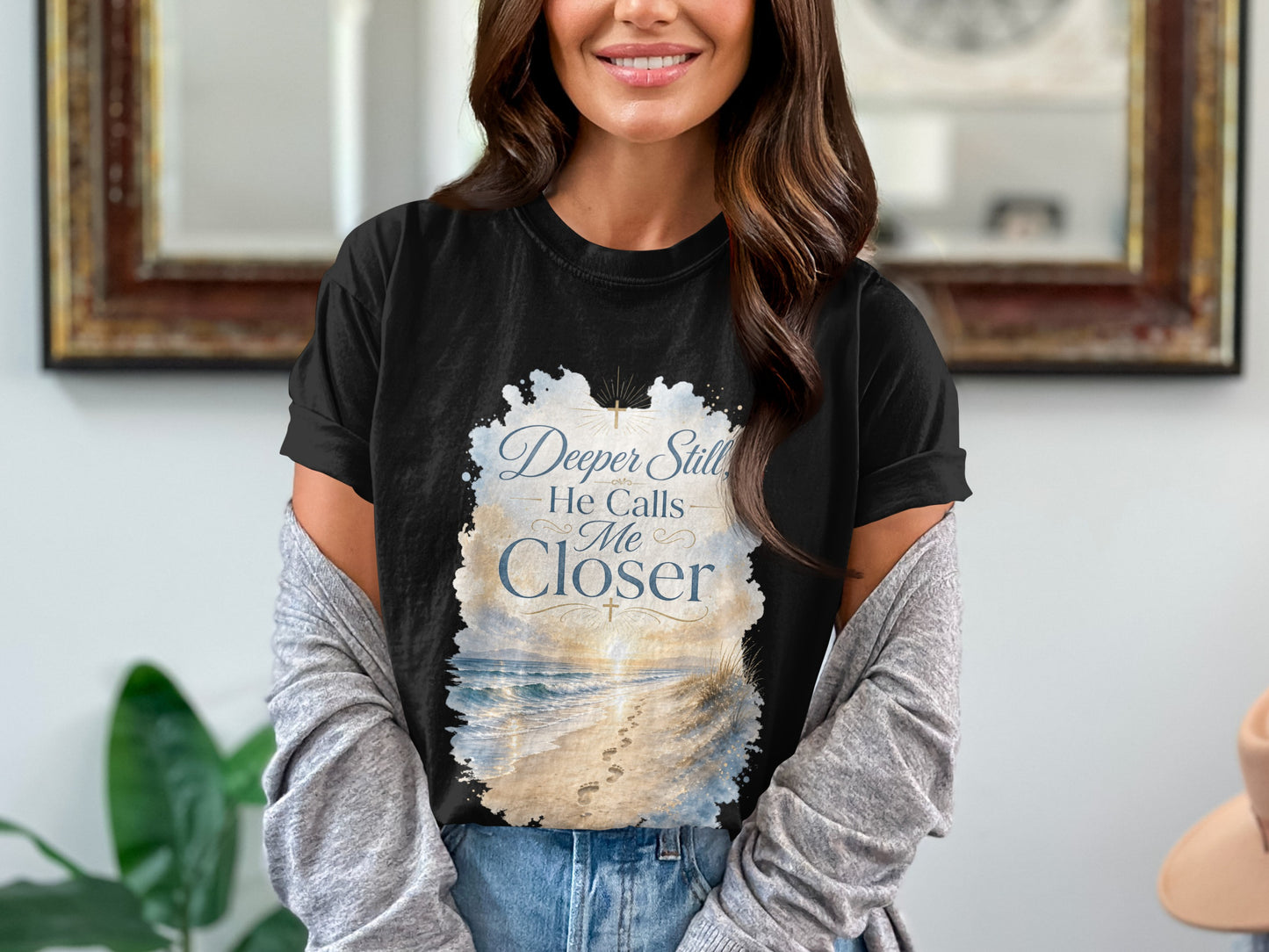 Black t-shirt with "Deeper Still He Calls Me Closer" and beach graphic.