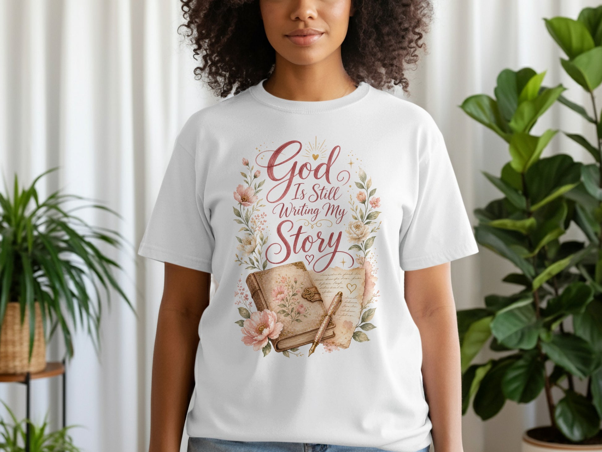 White t-shirt with "God Is Still Writing My Story" in script, surrounded by floral design.