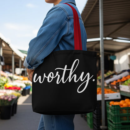 Black tote bag with white script text that reads "worthy."