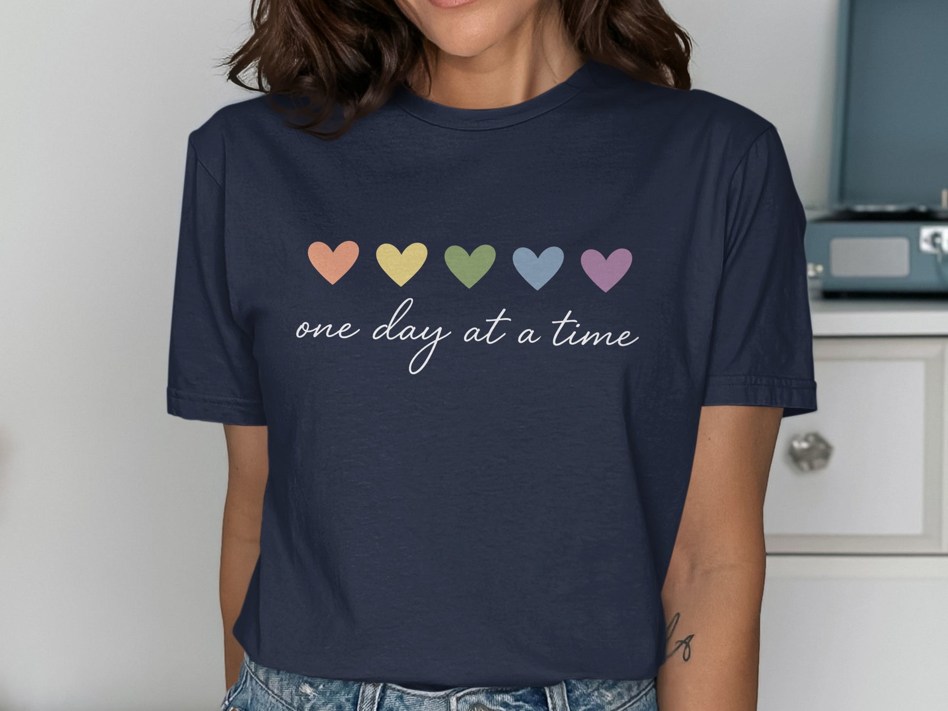 Navy t-shirt with pastel hearts and "one day at a time" text.