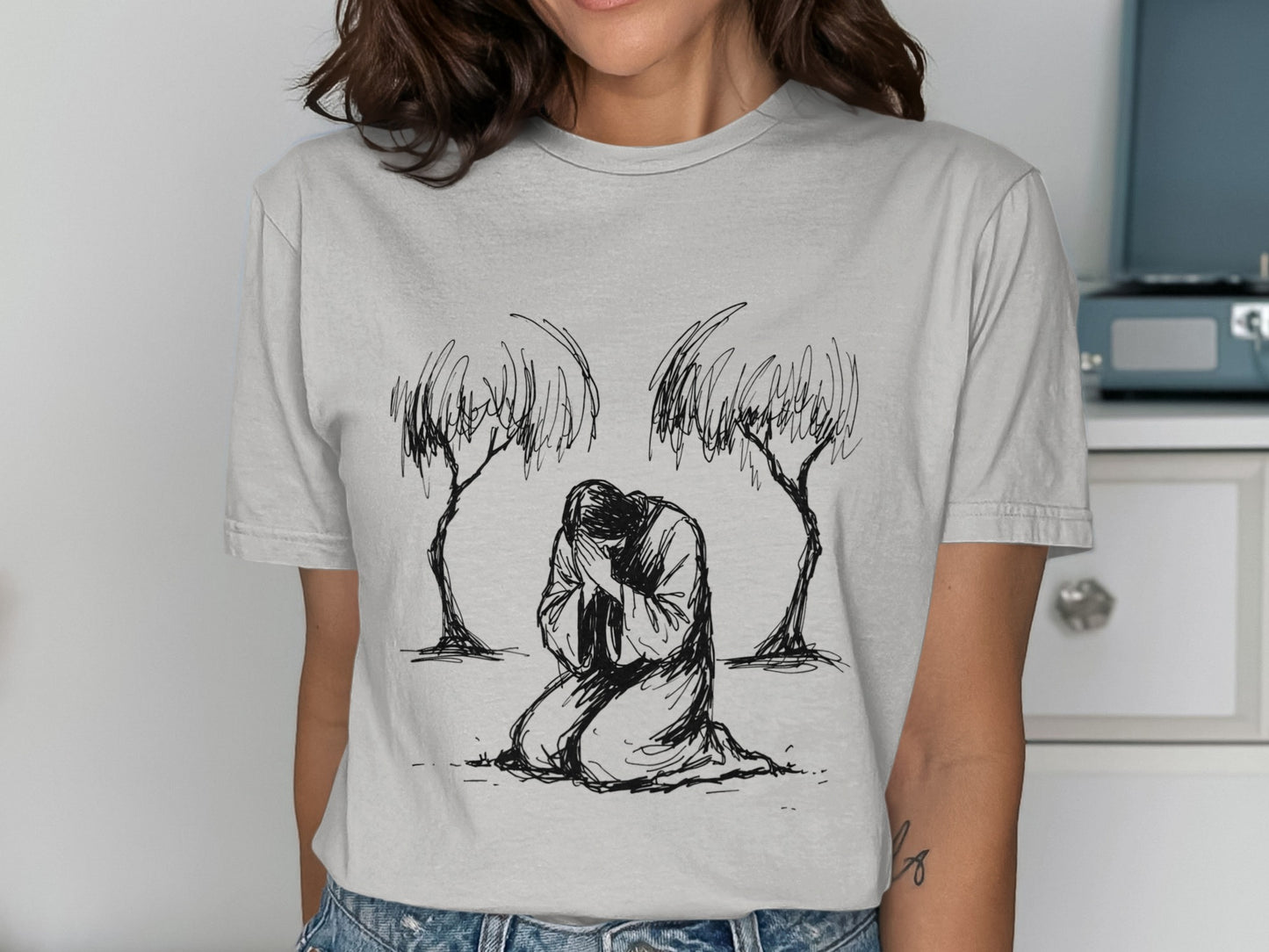 Line drawing of a person kneeling with head bowed between two sketched trees.