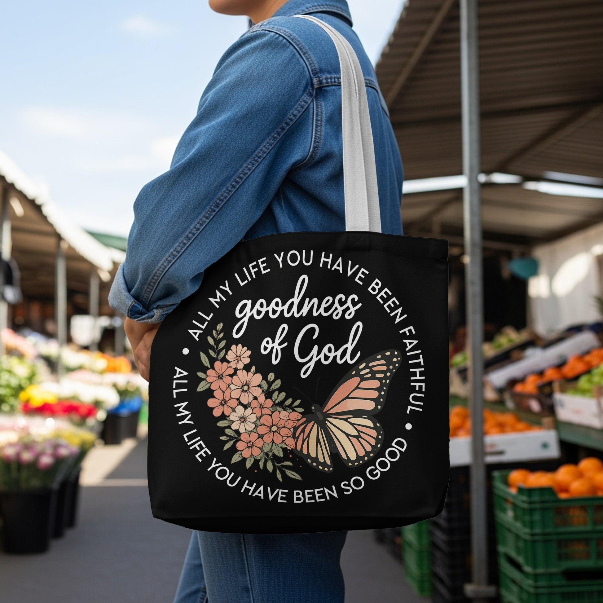 Black tote bag with "goodness of God" and floral butterfly design.
