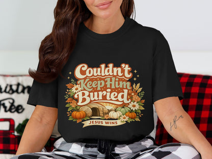 Black t-shirt with "Couldn't Keep Him Buried" and "Jesus Wins" text, tomb, and pumpkins.