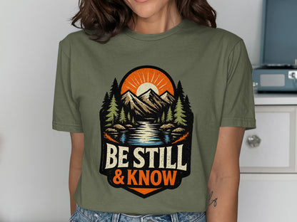 Olive t-shirt with mountain landscape graphic and "Be Still & Know" text.