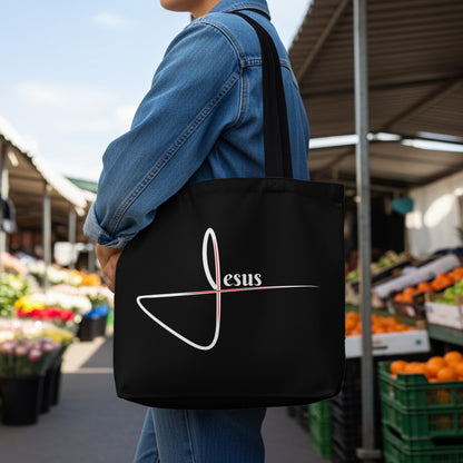 Black tote bag with a stylized white "Jesus" logo and red cross detail.
