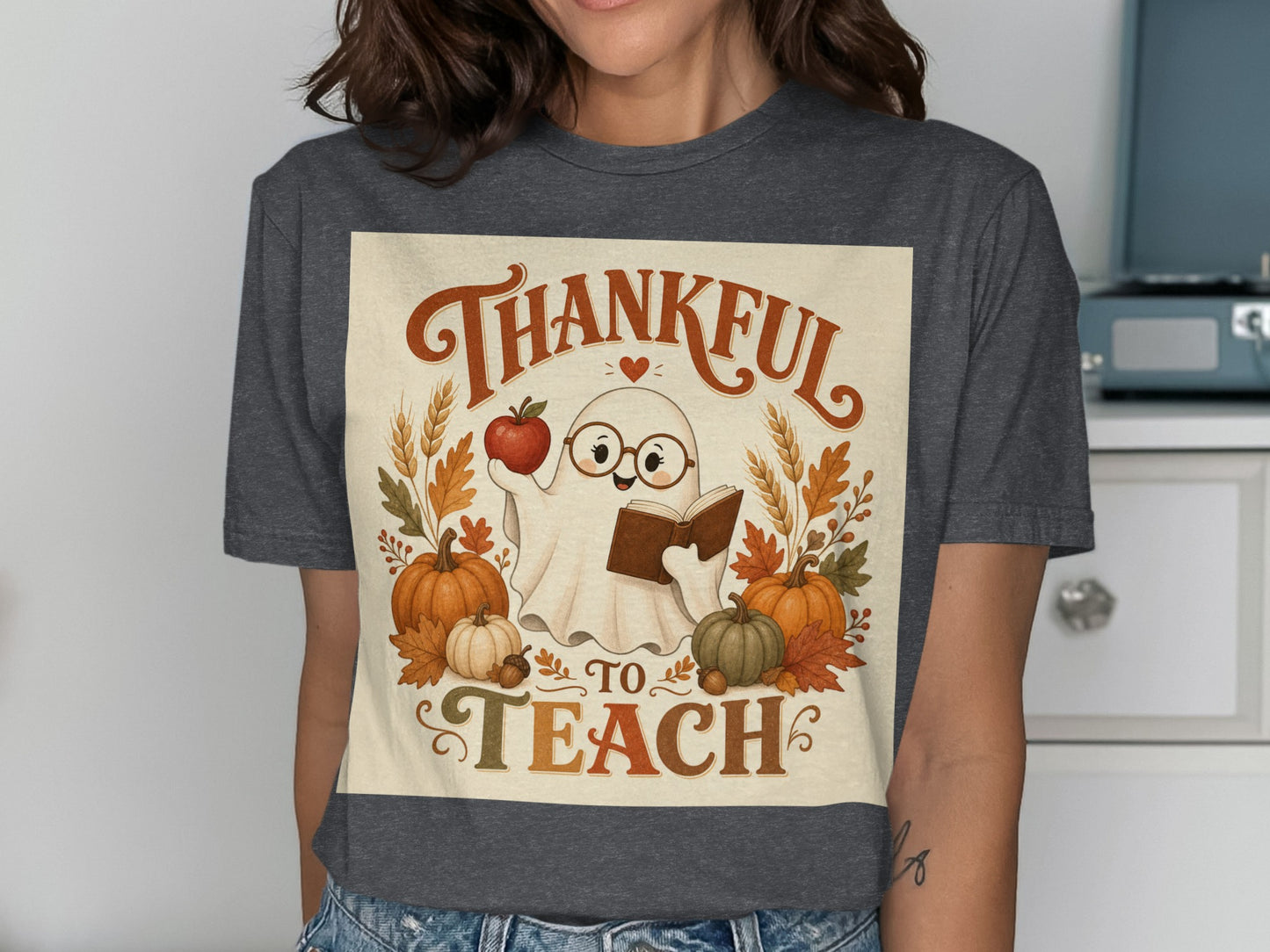 Thankful to Teach ghost holding apple and book surrounded by pumpkins and autumn leaves.