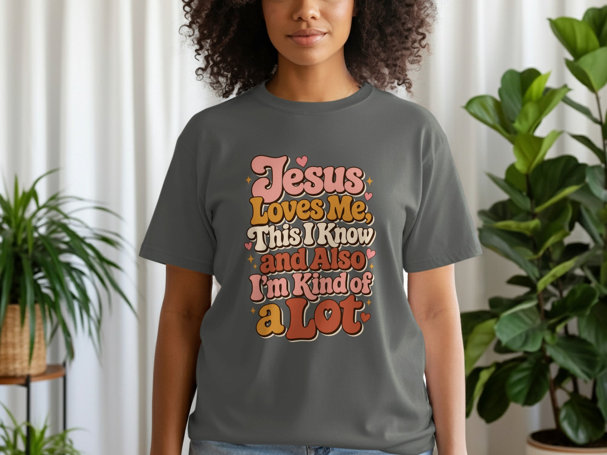 Dark grey t-shirt with retro text reading "Jesus Loves Me. This I Know and Also I'm Kind of a Lot."
