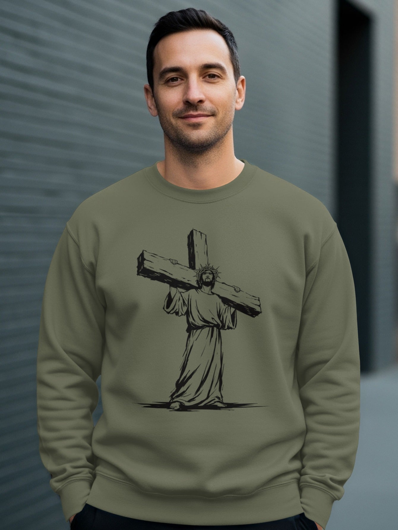 Man wearing olive green sweatshirt with graphic of Jesus carrying a cross.