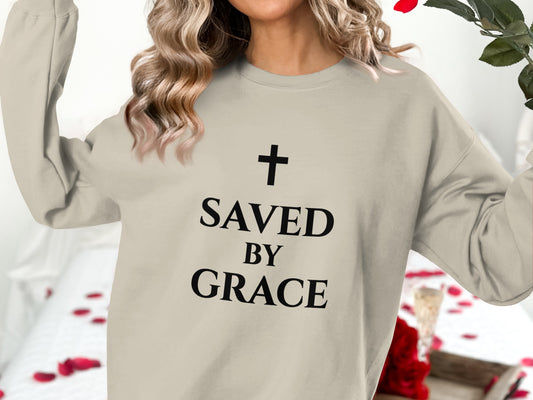 Light beige sweatshirt with "SAVED BY GRACE" and a cross design.