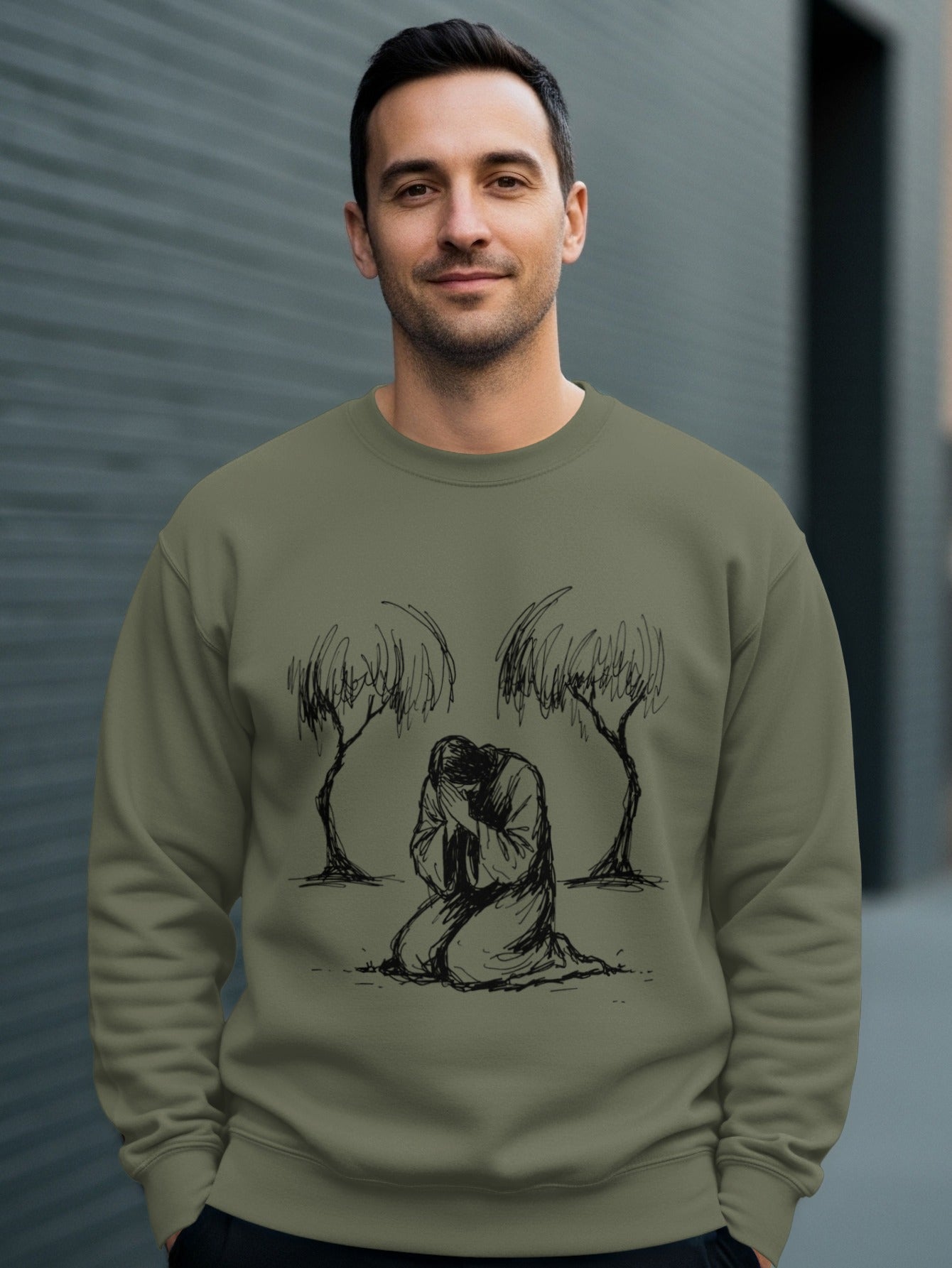 Man wearing green sweatshirt with Jesus praying between two trees graphic.