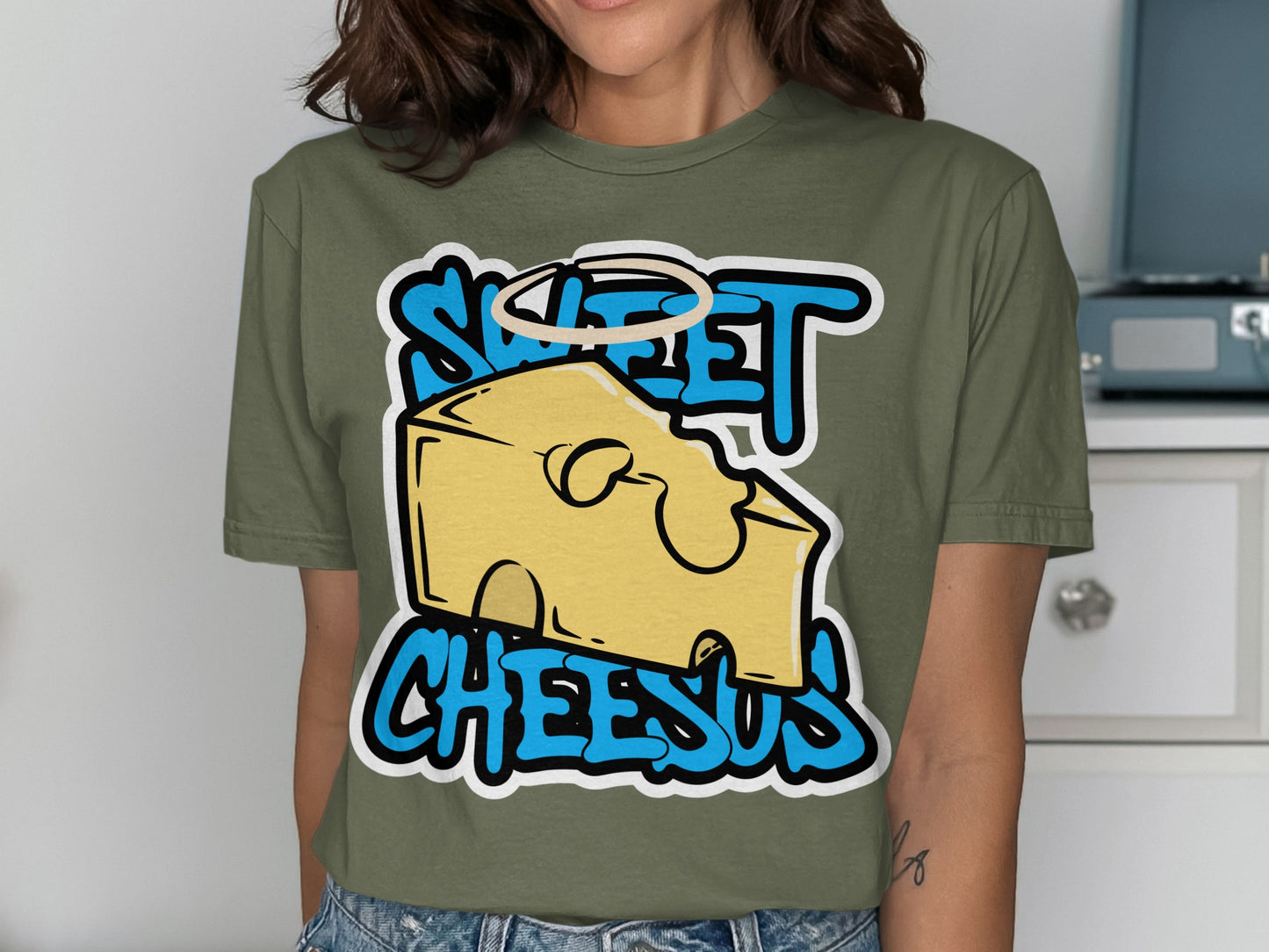 Green t-shirt with "Sweet Cheesus" text and cartoon cheese slice with halo.
