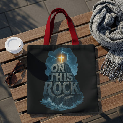 Black tote bag with "On This Rock" text, a cross on a mountain, and stormy background.