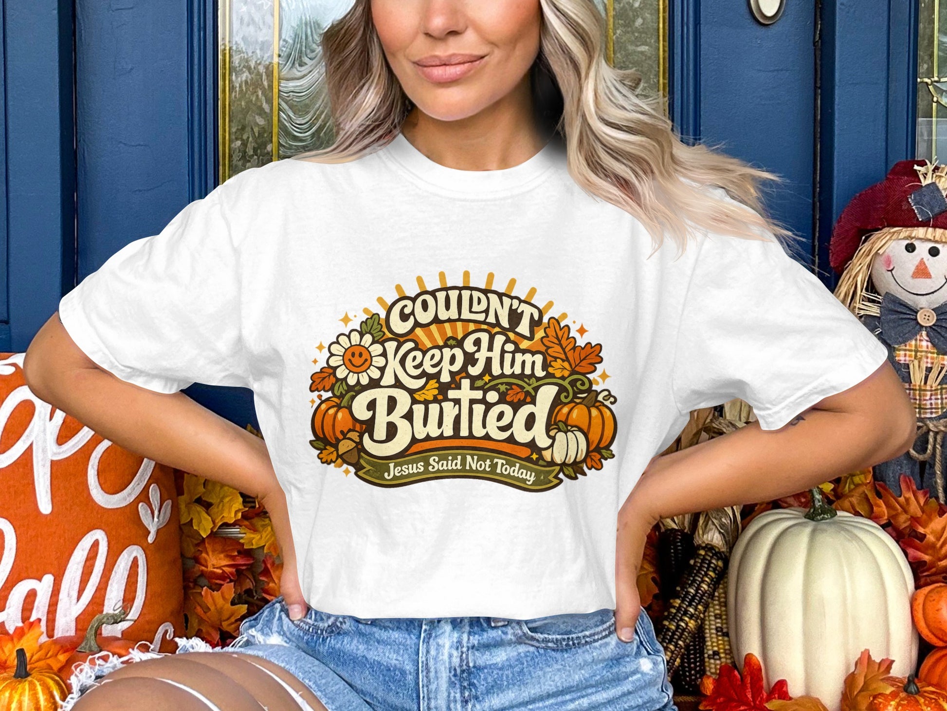 White t-shirt with "Couldn't Keep Him Burried" graphic and fall decorations.