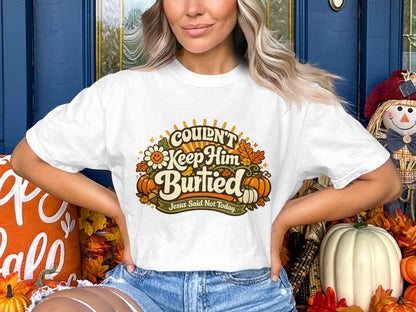 White t-shirt with "Couldn't Keep Him Burried" graphic and fall decorations.