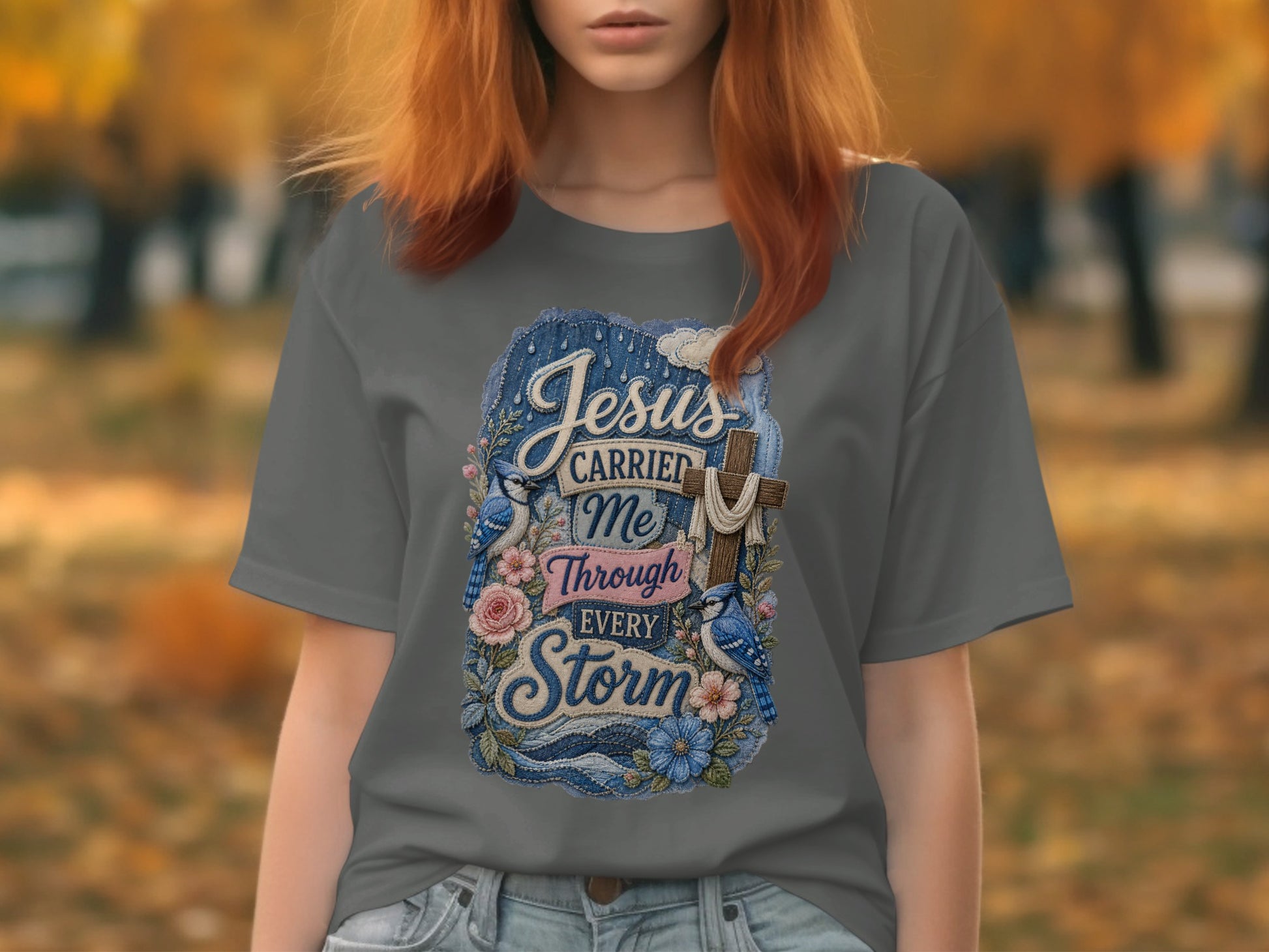 Grey t-shirt with "Jesus Carried Me Through Every Storm" cross and bluebirds design.