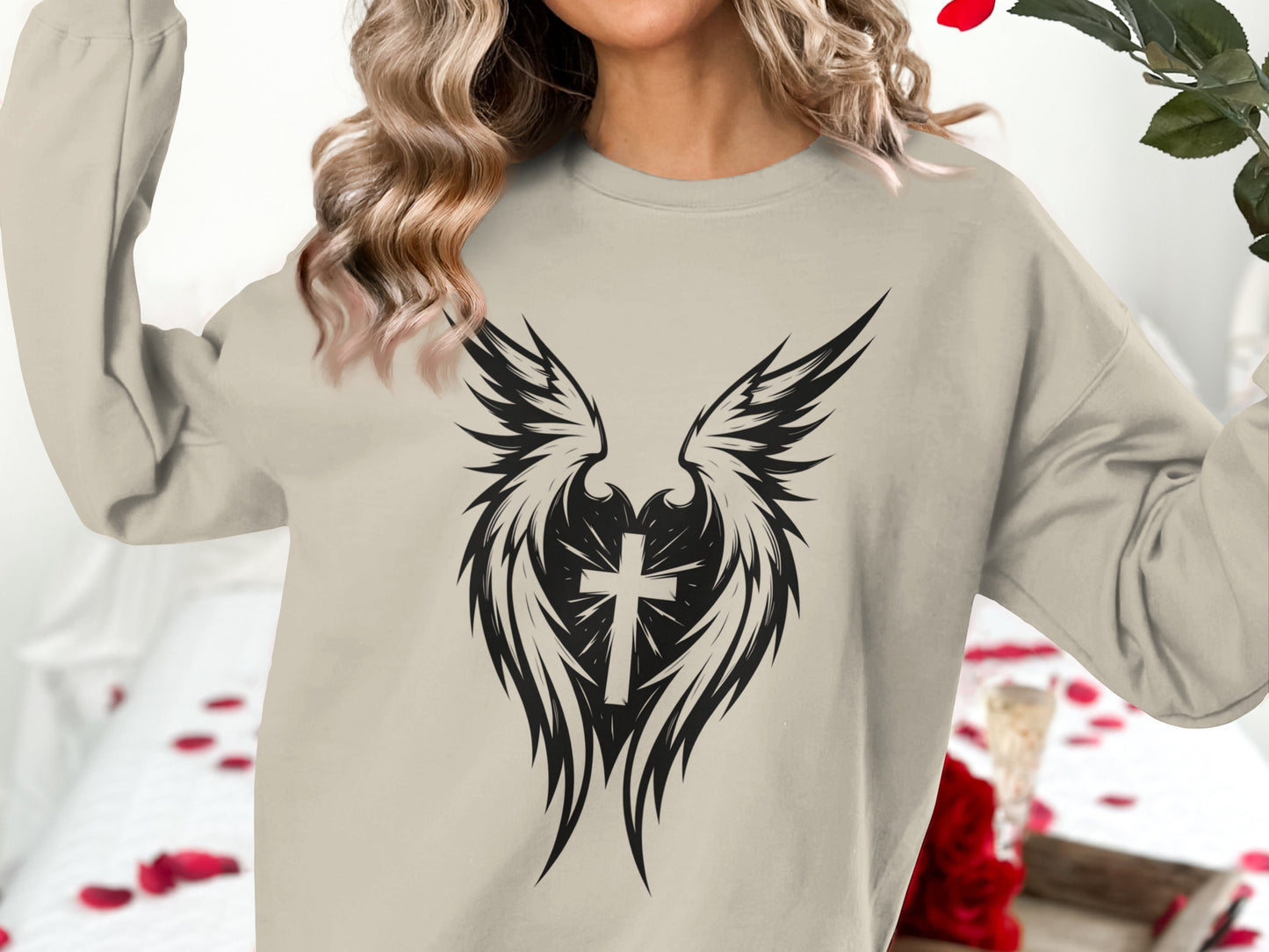 Crewneck sweatshirt with a winged cross graphic on a neutral background.
