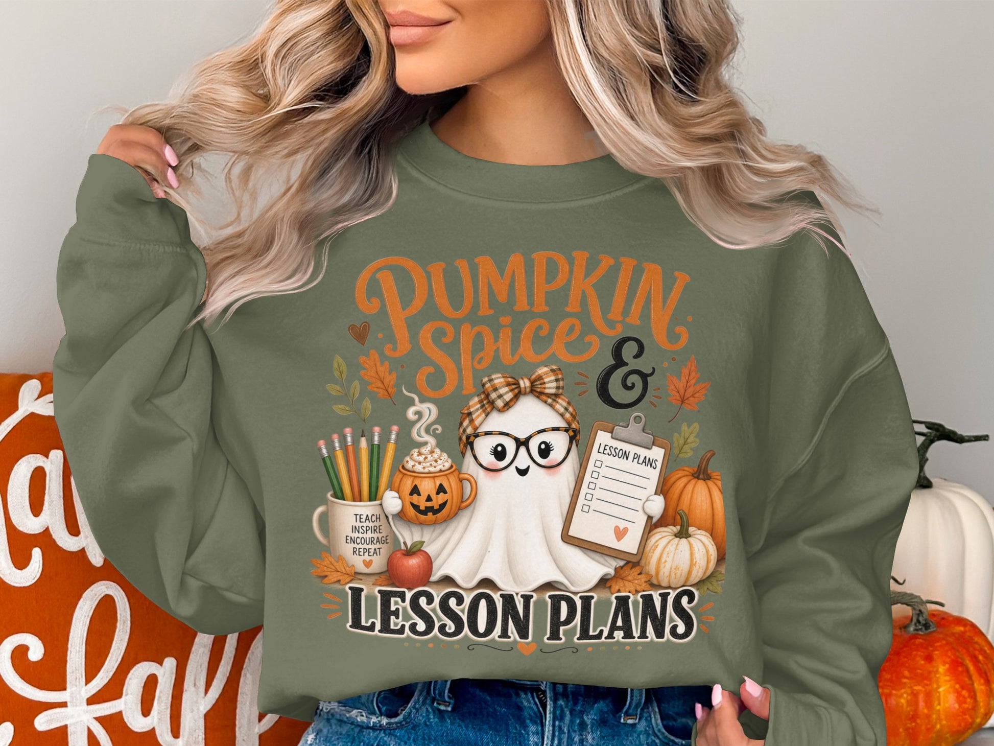 Ghost with glasses, pumpkin mug, and lesson plans on green sweatshirt.