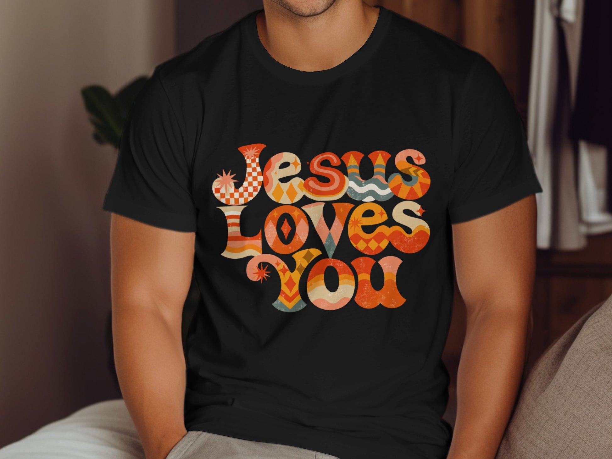 Black t-shirt with retro "Jesus Loves You" text design in colorful geometric patterns.