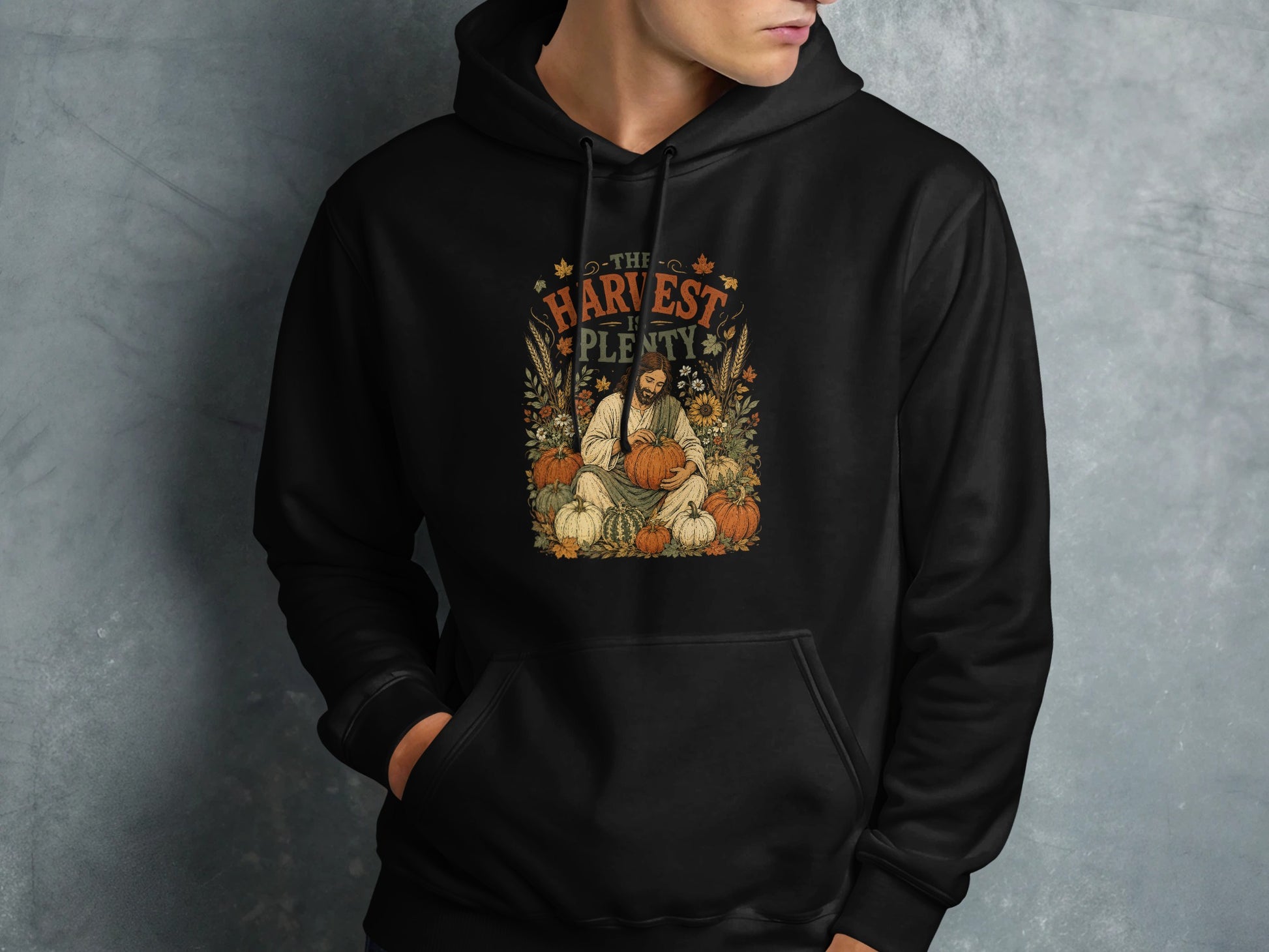 Black hoodie with autumn harvest design featuring a man holding a pumpkin.