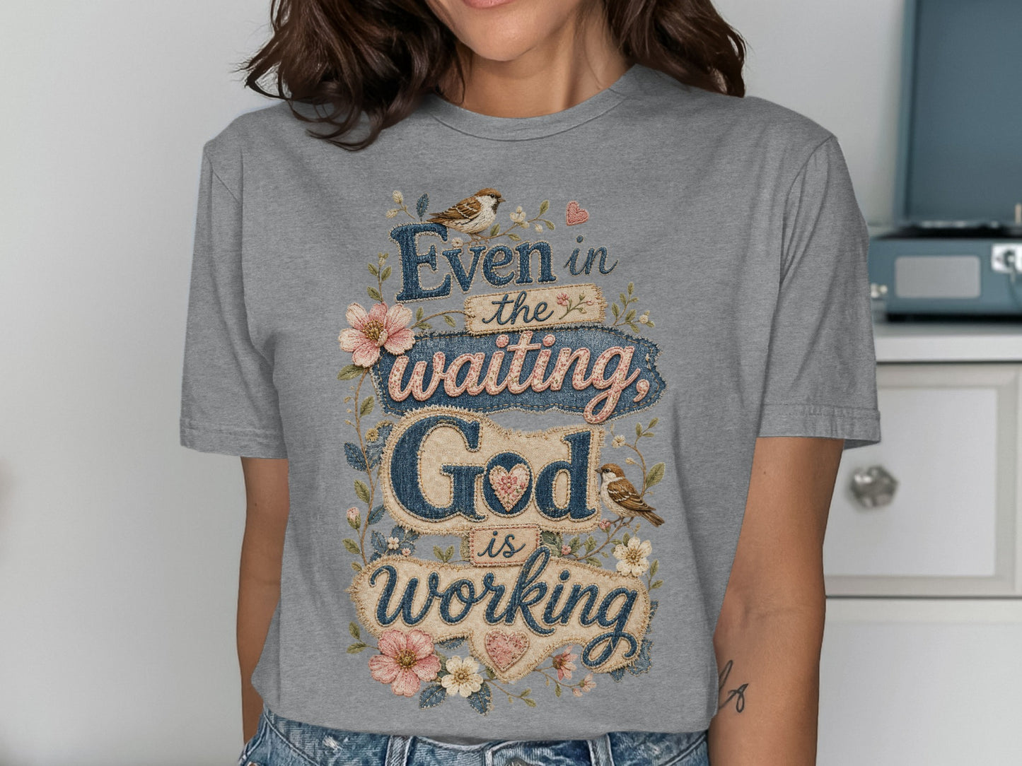 Grey t-shirt with "Even in the waiting God is working" text and floral accents.