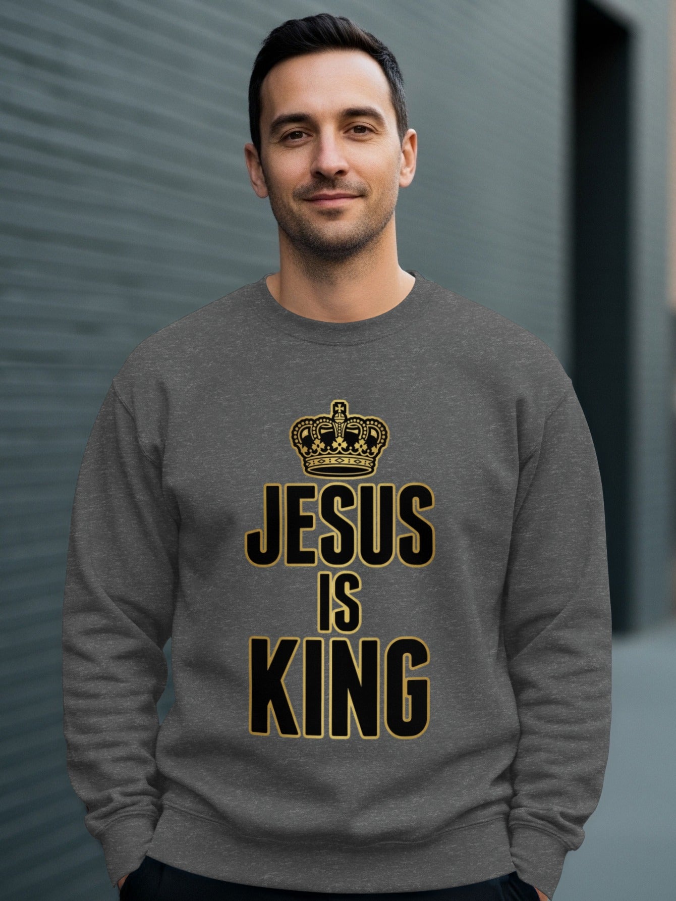 Man wearing a gray sweatshirt with "Jesus is King" and a crown logo.