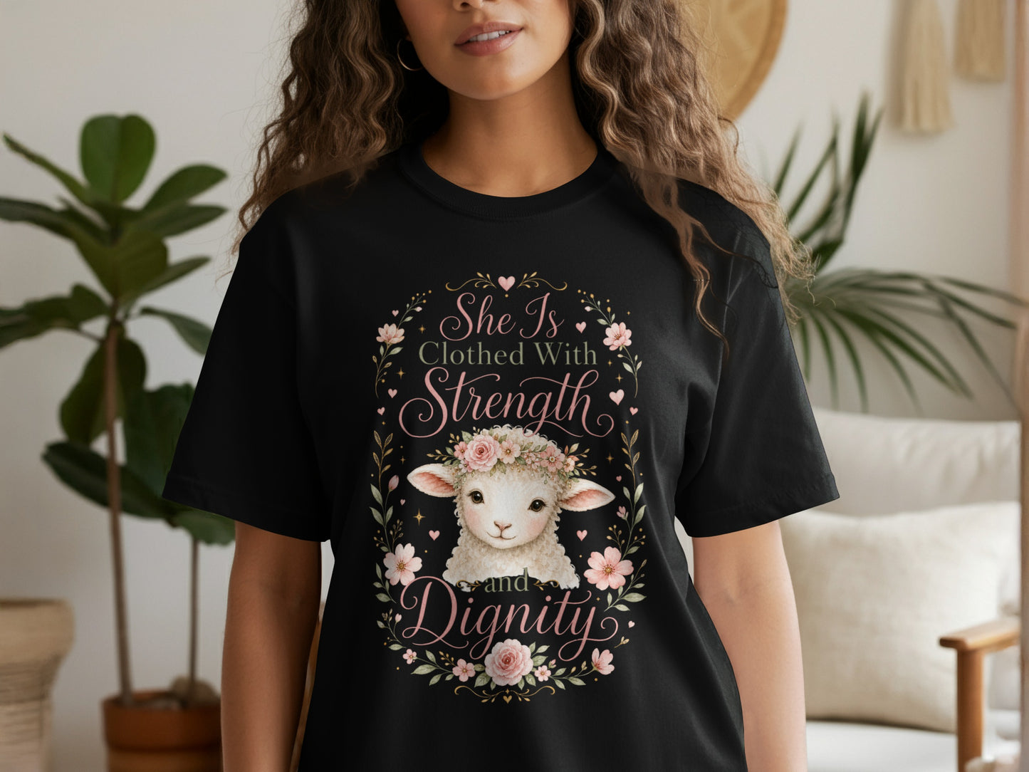 Black t-shirt with a lamb wearing a flower crown and text that reads "She Is Clothed With Strength and Dignity."