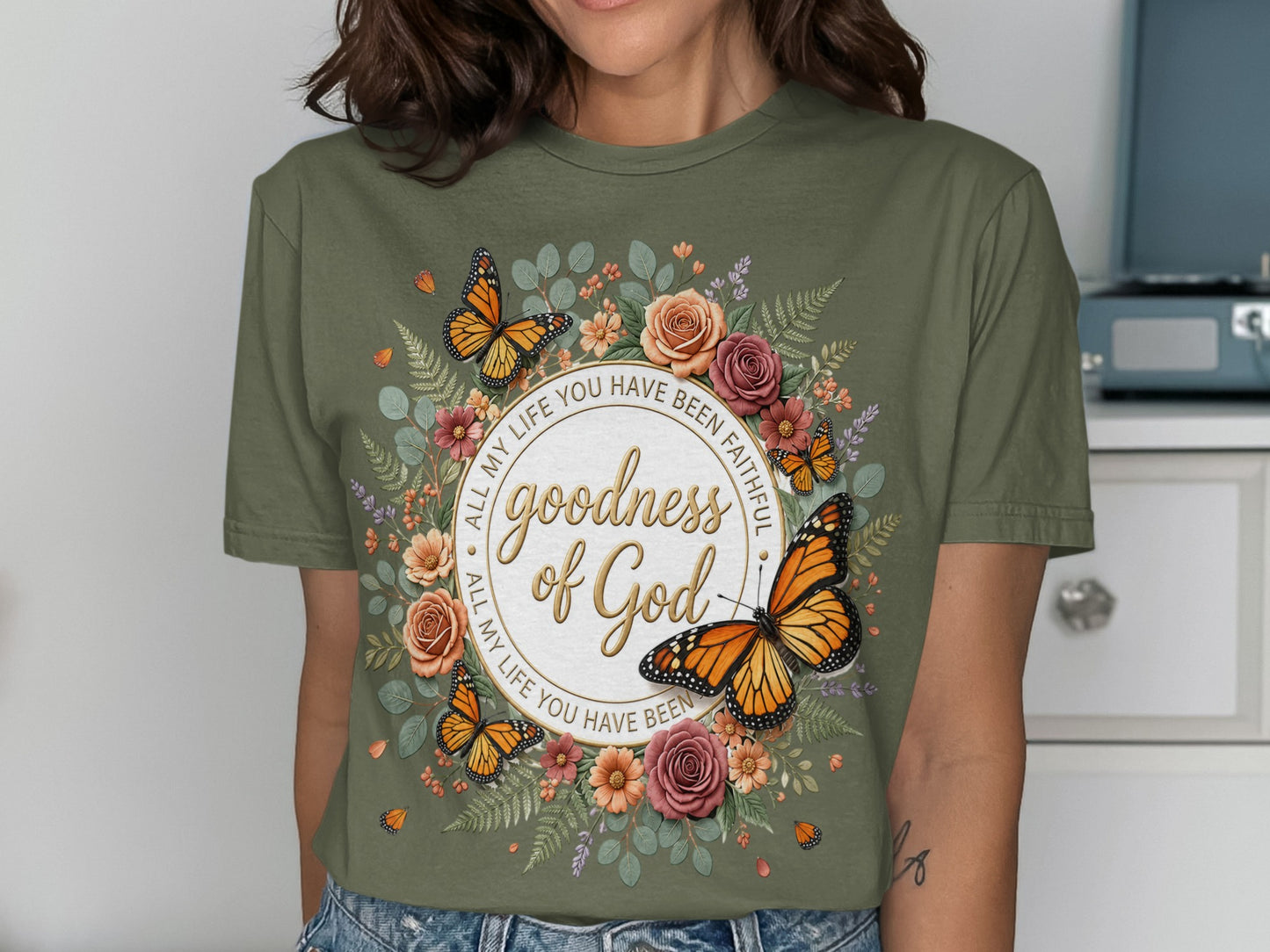 Green t-shirt with butterflies, flowers, and "goodness of God" text.