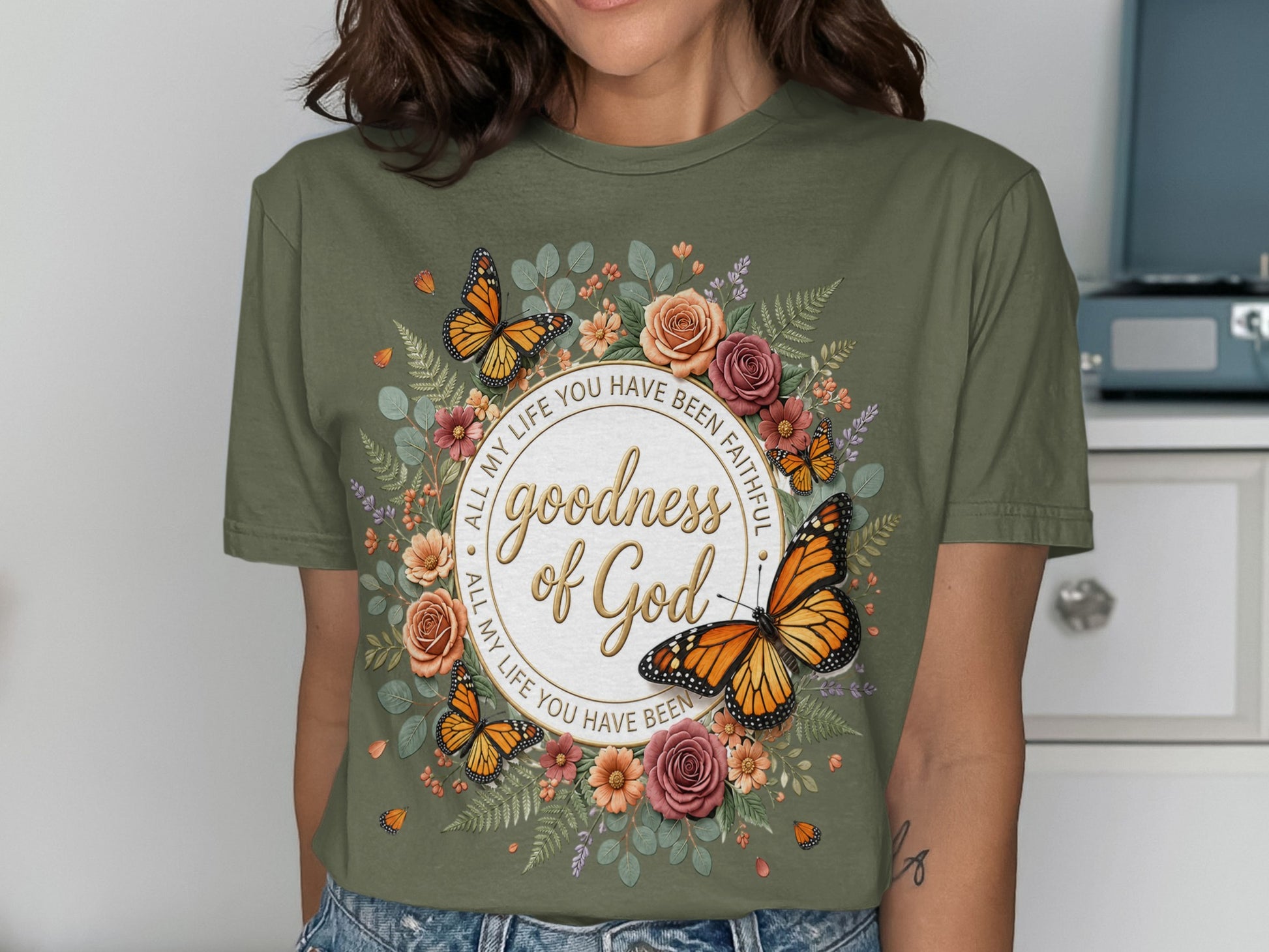 Green t-shirt with butterflies, flowers, and "goodness of God" text.