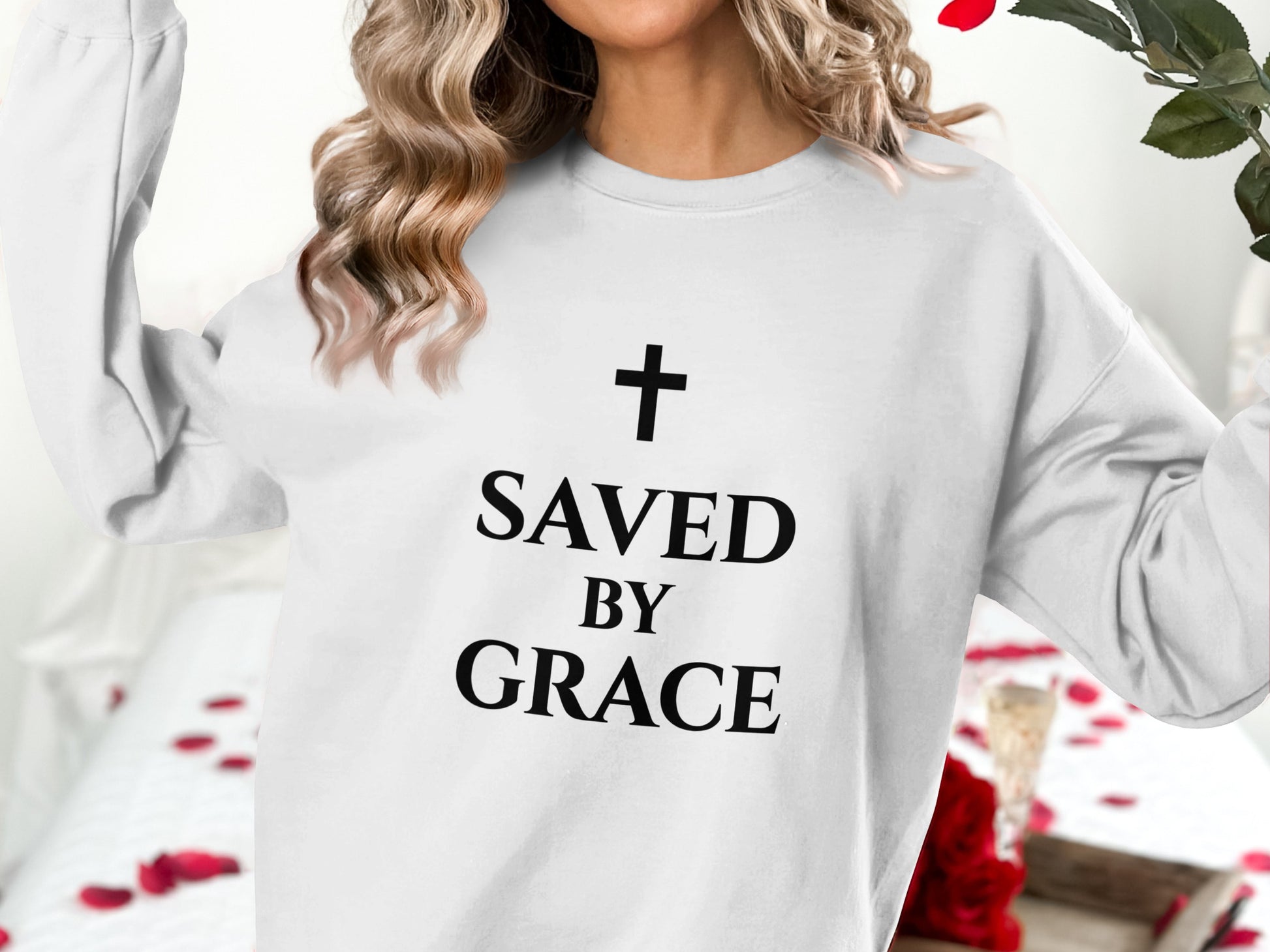 White sweatshirt with black "Saved by Grace" text and a cross graphic.