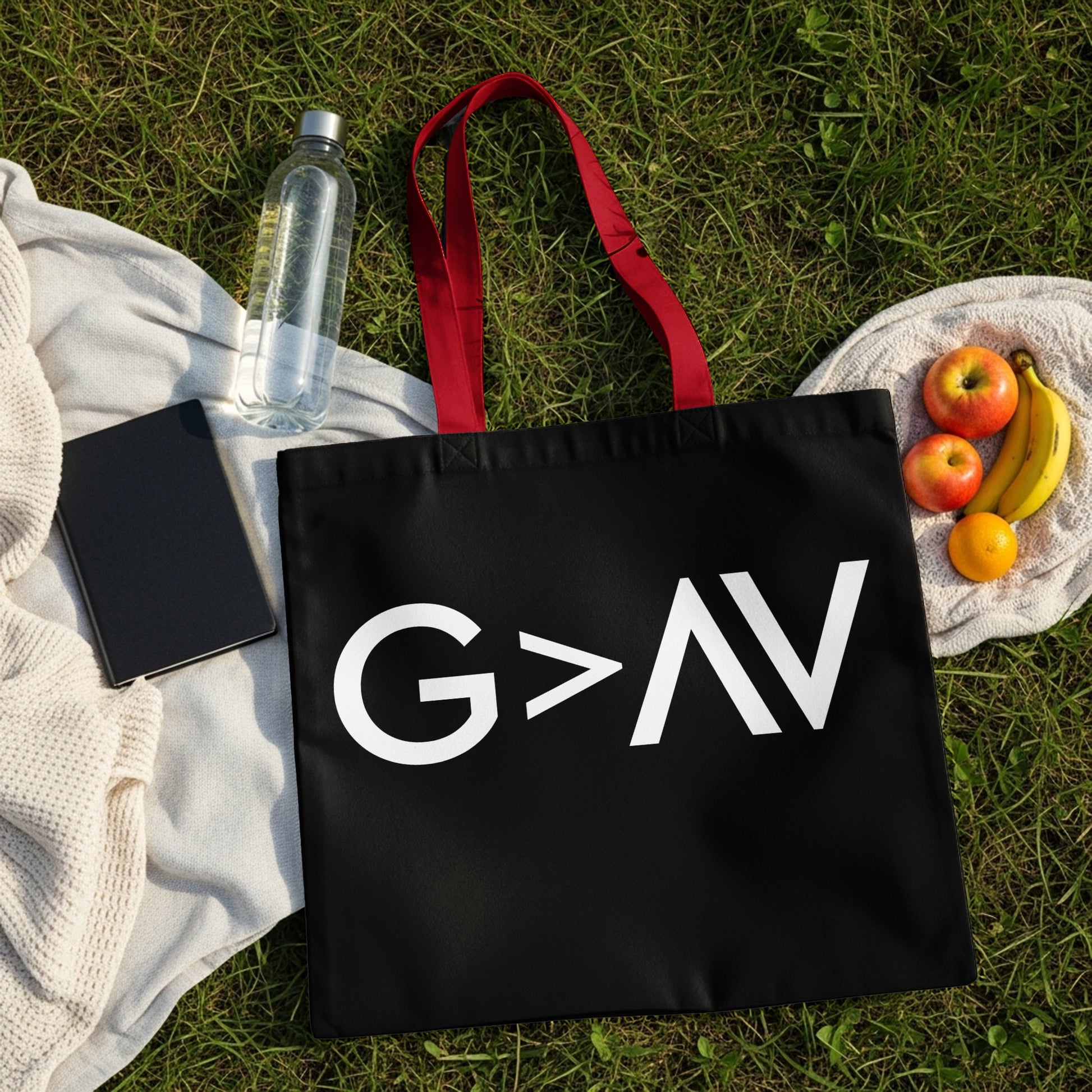 Black tote bag with white "G>AV" text and red handles on grass.