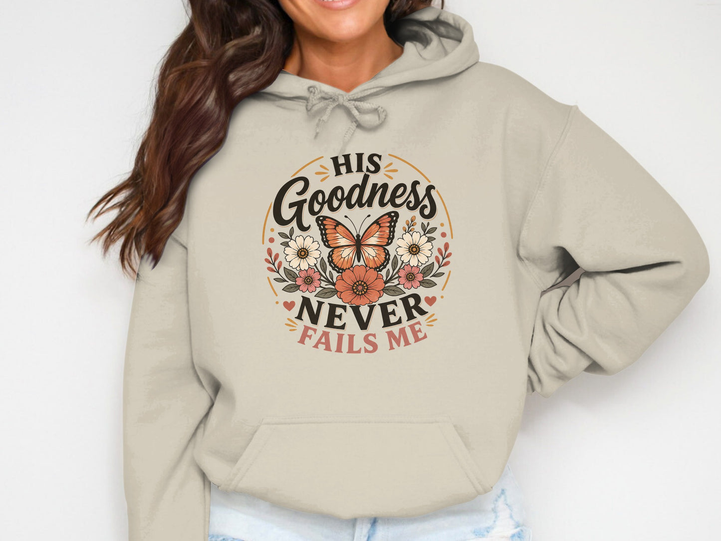 Beige hoodie with "His Goodness Never Fails Me" text and floral butterfly design.