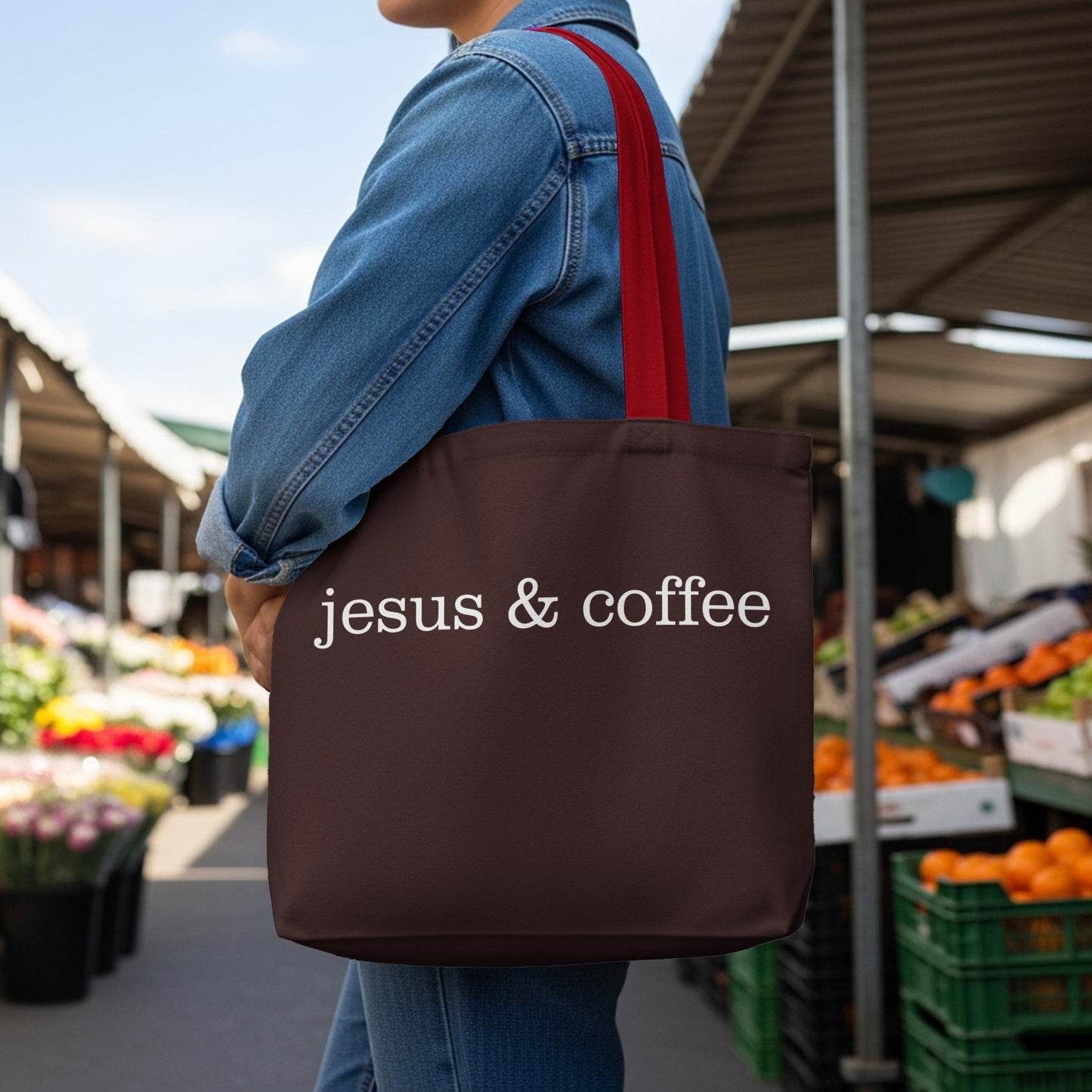 Brown tote bag with "jesus & coffee" in white text, held by person in denim jacket.