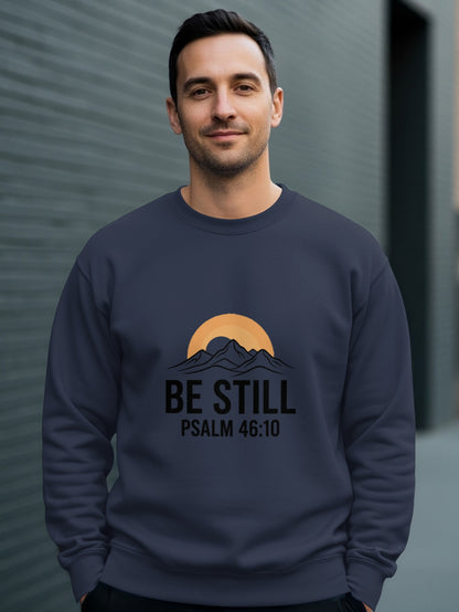 Man wearing a navy sweatshirt with "Be Still Psalm 46:10" text and mountain sunset graphic.