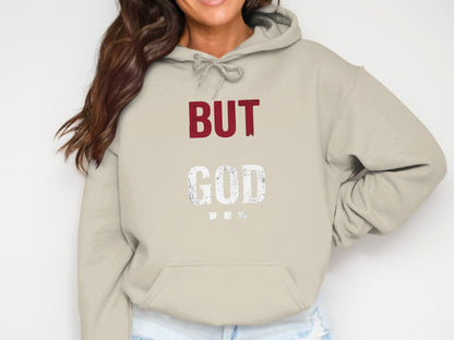 Beige hoodie with "BUT GOD" printed in burgundy and white distressed letters.