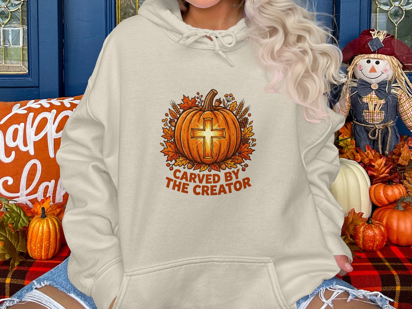 Cream hoodie with carved pumpkin design and "Carved by the Creator" text.
