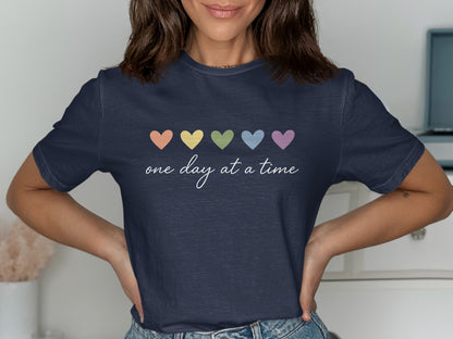 Dark blue t-shirt with pastel hearts and "one day at a time" text.