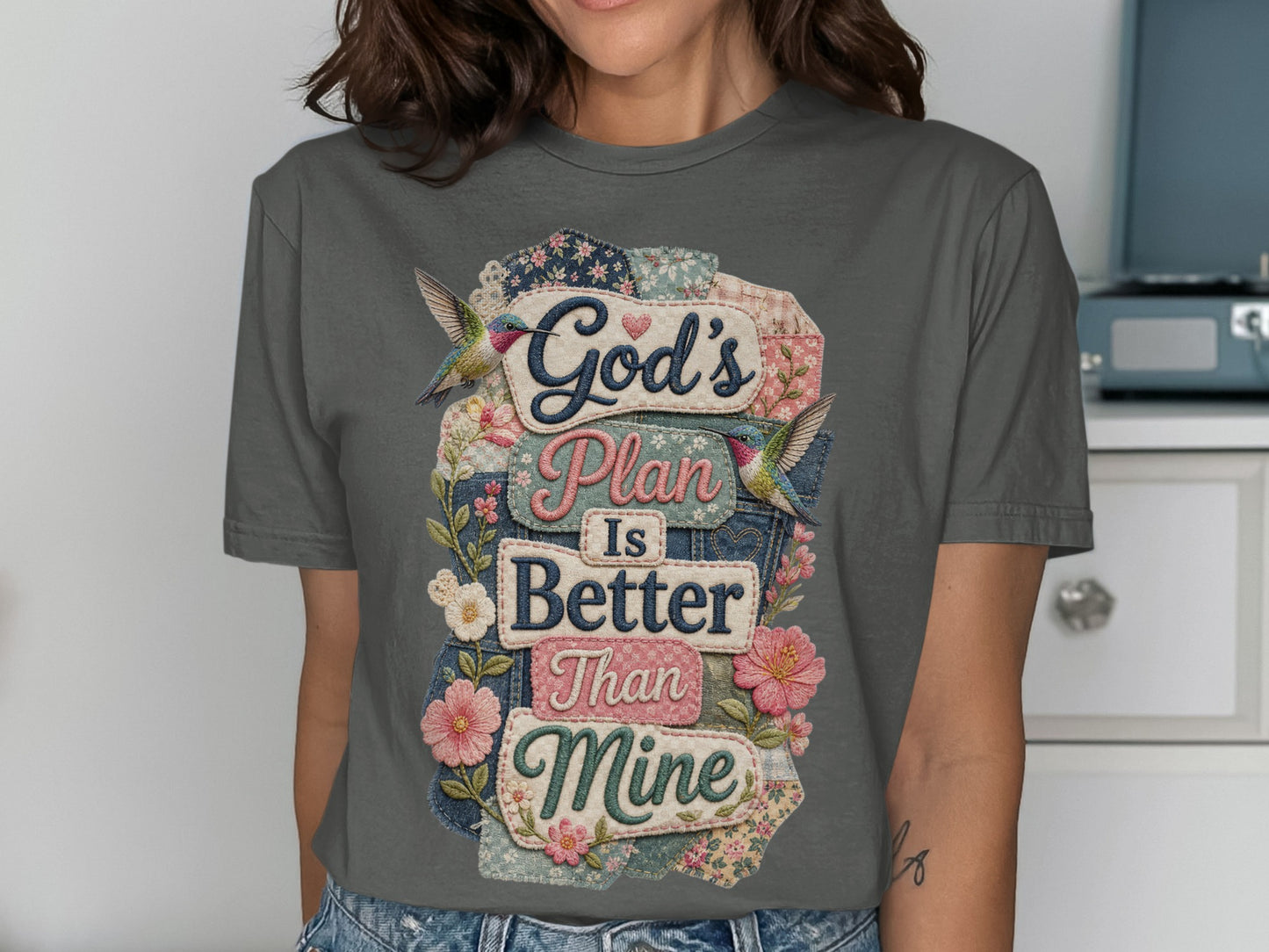 Gray t-shirt with "God's Plan Is Better Than Mine" text surrounded by floral patches and hummingbirds.