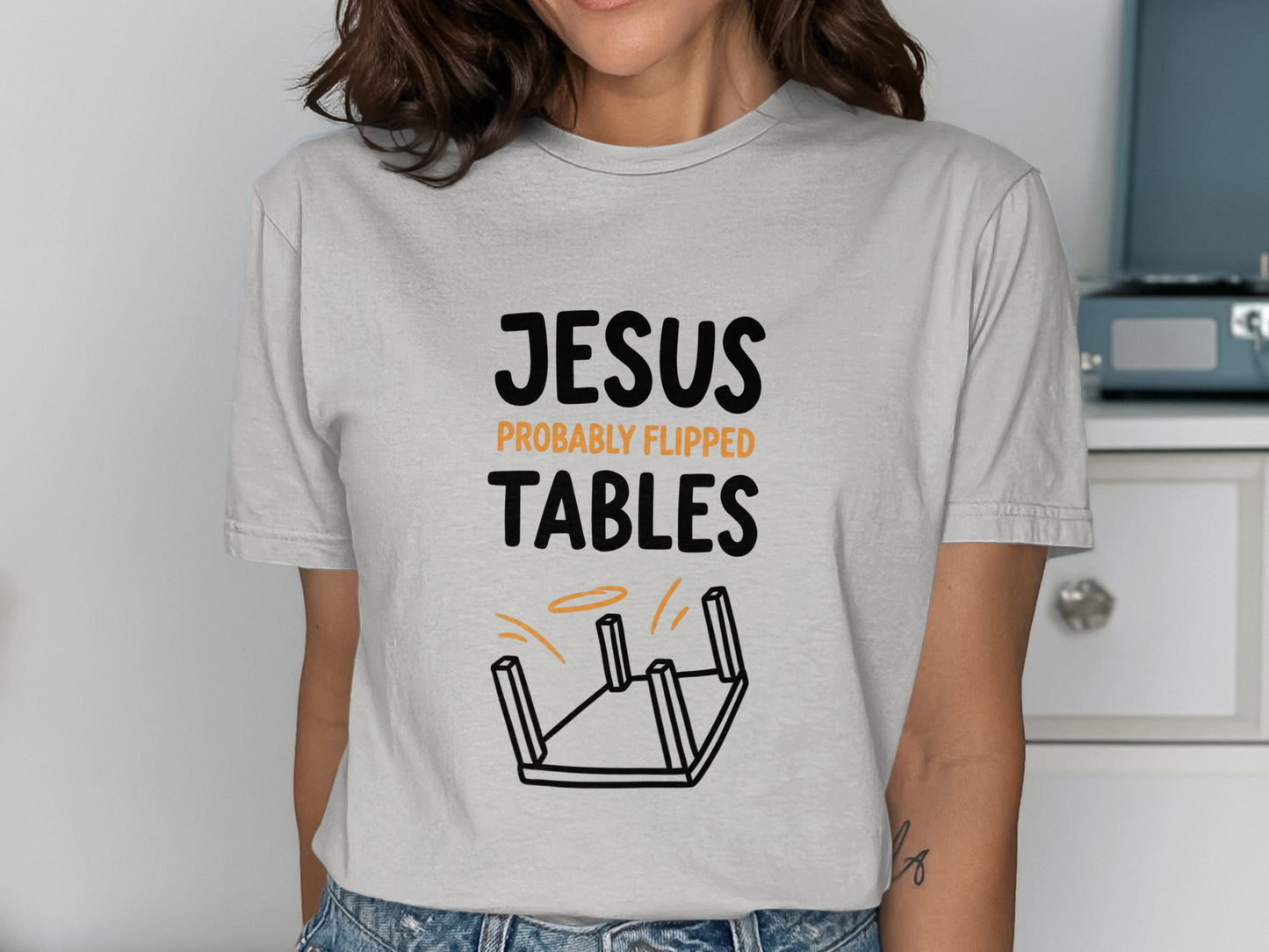 Grey t-shirt with "Jesus flipped tables" and an overturned table illustration.