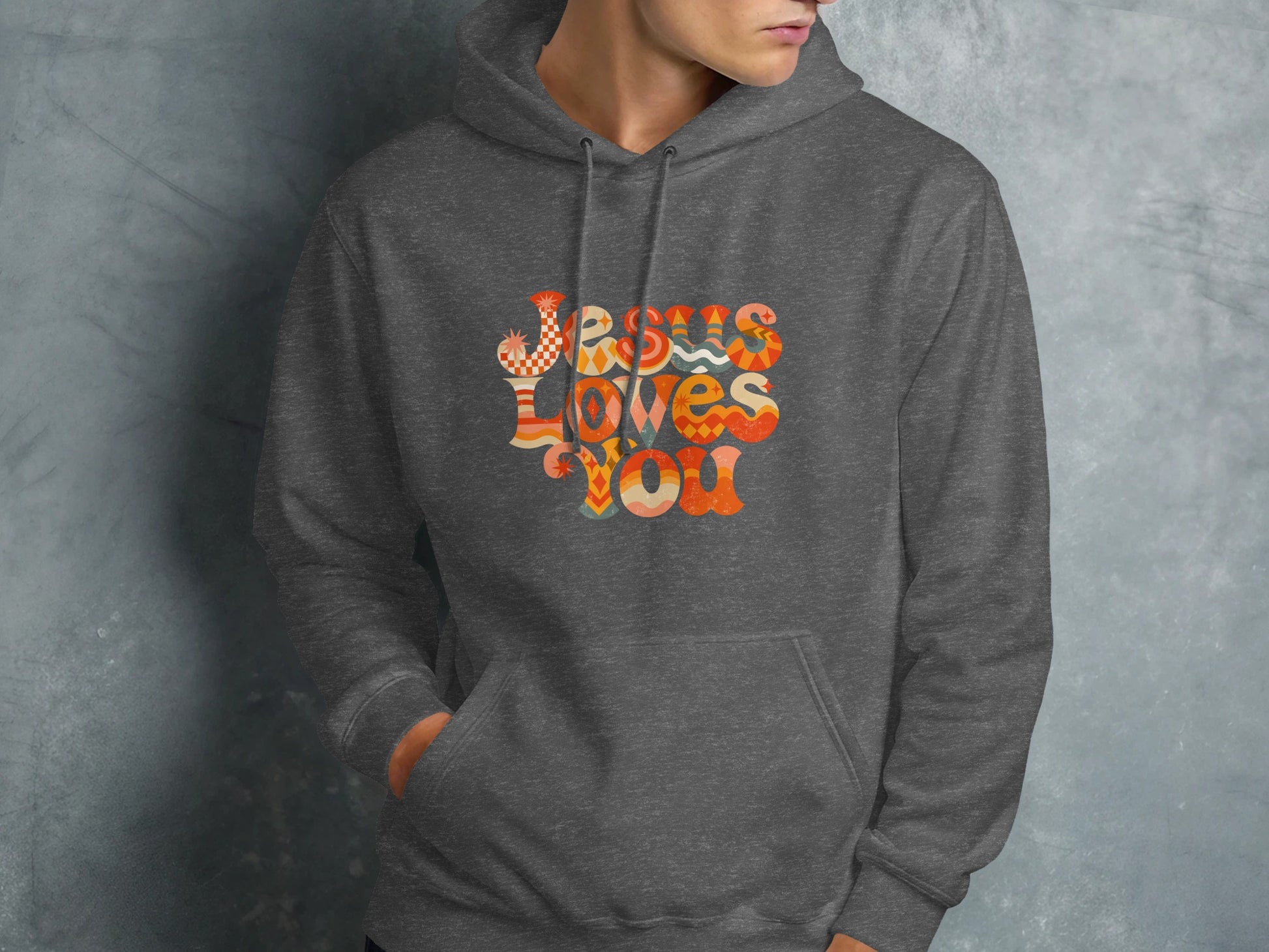 Dark gray hoodie with "Jesus Loves You" graphic in colorful retro font.