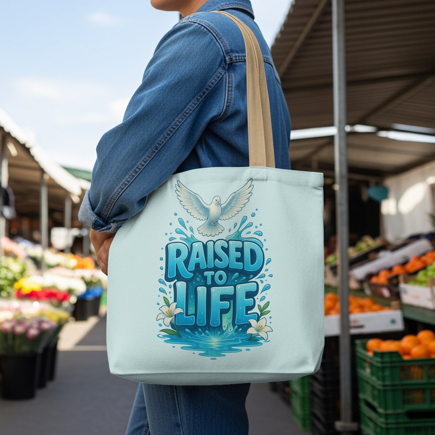 Light blue tote bag with white dove and text "RAISED TO LIFE"