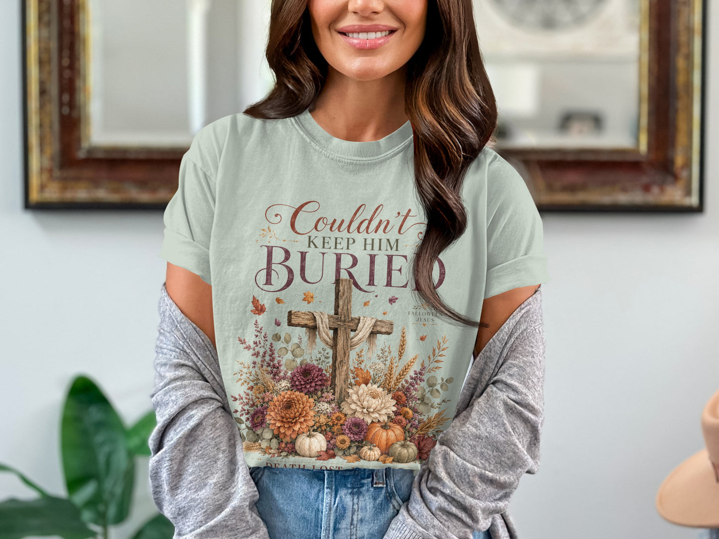 Light blue t-shirt with rustic cross and flowers graphic, reads "Couldn't Keep Him Buried."